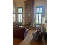 Spacious living room with a brick fireplace, hardwood floors, and bright windows with wood shutters at 14131 E Baltic Pl, Aurora, CO 80014