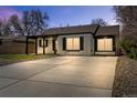 Charming painted brick home featuring a large driveway, covered porch, and manicured landscaping at 2441 Niagara St, Denver, CO 80207