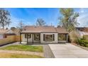 Charming painted brick home featuring a large driveway, covered porch, and manicured landscaping at 2441 Niagara St, Denver, CO 80207