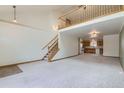 Open-concept living area with vaulted ceilings, staircase, and view to the kitchen, perfect for entertaining at 2585 E Egbert St, Brighton, CO 80601