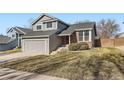 Two-story home features a well-kept front lawn, gray siding, brick accents, and a two-car garage at 1011 Thames St, Highlands Ranch, CO 80126