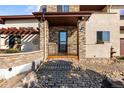 Inviting front entrance featuring stone accents, a covered porch, and manicured landscaping at 4473 Echo Dr, Larkspur, CO 80118