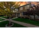 Landscaped front yard with trees and green grass leading to a well-maintained home with a covered porch and stone accents at 4589 Quandary Peak St, Brighton, CO 80601