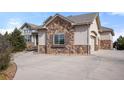 Beautiful home exterior with stone accents, three-car garage, and a circular driveway at 6425 Tremolite Dr, Castle Rock, CO 80108