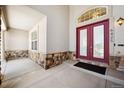 Inviting front porch with a red double door entrance featuring glass panels and a stone accent wall at 6425 Tremolite Dr, Castle Rock, CO 80108