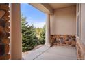 Covered patio with stone accents offers a view of the tree-lined neighborhood at 6425 Tremolite Dr, Castle Rock, CO 80108