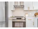 Close up of the new stainless steel oven with range hood and white cabinets in a renovated kitchen at 1240 S Chase Ct, Lakewood, CO 80232