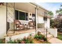 Covered porch with two wicker chairs and manicured landscaping including a flower garden at 5885 S Huron St, Littleton, CO 80120