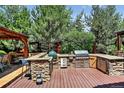 Outdoor kitchen with stainless steel grill, stone counters and wooden deck perfect for entertaining at 4649 Spinning Wheel Dr, Brighton, CO 80601