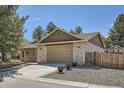 Front exterior featuring a two-car garage, brick facade, mature trees, and tasteful landscaping at 5461 S Youngfield Ct, Littleton, CO 80127