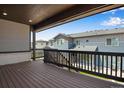 Spacious covered deck featuring wood flooring and black railing, with a neighborhood view at 6881 Oak Canyon Cir, Castle Pines, CO 80108