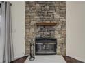 Stone fireplace featuring a wooden mantel, black metal fireplace doors, and decorative fireplace tools at 218 Wright St # 303, Lakewood, CO 80228