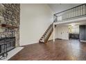 Open-concept living room with hardwood floors, a stone fireplace, staircase to a loft, and an adjacent kitchen at 218 Wright St # 303, Lakewood, CO 80228