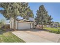 Wide driveway leading to a two-car garage, complemented by mature trees providing shade and privacy at 15531 E Jewell Pl, Aurora, CO 80013