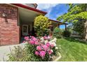 Inviting entryway featuring beautiful pink and white peonies, red brick accents, and a covered porch at 2912 Lake Park Way, Longmont, CO 80503