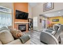 Cozy living room features a brick fireplace, soaring ceilings, and ample natural light for comfortable living at 13323 Birch Cir, Thornton, CO 80241