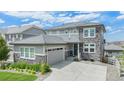 Attractive two-story home with stone accents, gray siding, and a large garage, set on a well-maintained lawn at 3453 Pacific Peak Dr, Broomfield, CO 80023