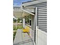 A close-up view of the gray home's porch showcasing a vibrant yellow bench and decorative white awning at 98 N 12Th Ave, Brighton, CO 80601