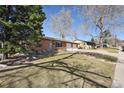 A single-story brick home with a two car garage and well-maintained lawn and mature trees at 2813 S Zenobia St, Denver, CO 80236