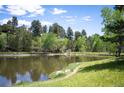 Scenic pond with trees and hillside homes in the background creating a peaceful natural setting at 23612 Pondview Pl # A, Golden, CO 80401