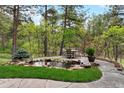 Landscaped backyard with a stone patio, water feature, and mature trees at 646 Ruby Trust Dr, Castle Rock, CO 80108
