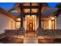 Grand entryway with stone pillars, wood door with decorative wreath, and stylish lighting at 646 Ruby Trust Dr, Castle Rock, CO 80108