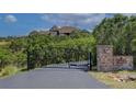 Gated driveway entrance with stone pillars ensuring privacy to the residence, surrounded by mature trees at 2941 Castle Butte Drive Dr, Castle Rock, CO 80109