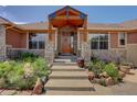 Inviting front entrance with a custom wood door, stone accents, and professionally landscaped front yard at 2941 Castle Butte Drive Dr, Castle Rock, CO 80109