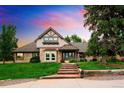 Beautiful home featuring a stone facade, brick accents, mature trees, and a manicured lawn at 17053 E Jamison Ave, Centennial, CO 80016