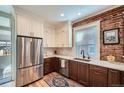 Modern kitchen featuring two-tone cabinetry, stainless steel appliances, and exposed brick accent wall at 636 N Logan St, Denver, CO 80203