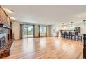 Open-concept living space with a brick fireplace, hardwood floors, and access to the kitchen at 5583 Thunder Hill Rd, Parker, CO 80134