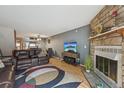 Cozy living room with a stone fireplace, wood floors, and a comfortable brown leather sofa at 912 S Paris Ct, Aurora, CO 80012