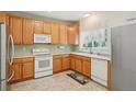 Functional kitchen with wood cabinets, white appliances, a garden window, and tile flooring at 7371 S Mobile St, Aurora, CO 80016
