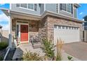 Inviting front porch featuring a red door, stone accents and a cozy seating area at 4419 N Quatar Ct, Aurora, CO 80019