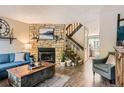 Cozy living room featuring a stone fireplace, hardwood floors, and comfortable blue sofa at 8252 S Fillmore Cir, Centennial, CO 80122
