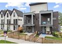 Modern home with brick facade, balconies, fenced yard, and inviting landscaping at 1302 N Stuart St, Denver, CO 80204