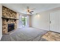 Living room with a stone fireplace, sliding glass doors to a balcony, and neutral carpeting at 4400 S Quebec St # D203, Denver, CO 80237