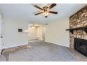 Open-concept living room featuring neutral carpeting, a ceiling fan, and a stone fireplace at 4400 S Quebec St # D203, Denver, CO 80237
