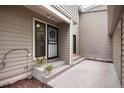 Exterior view of home's front entrance featuring a secure, gated door, flower pots, and a concrete porch at 7925 W Layton Ave # 605, Littleton, CO 80123