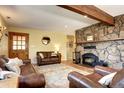 Cozy living room with a beautiful stone fireplace, wooden beam, and comfortable leather furniture at 10381 Hondah Dr, Littleton, CO 80127