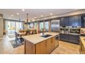 Open concept kitchen boasts modern appliances, an island, and hardwood floors at 9006 E 60Th Ave, Denver, CO 80238