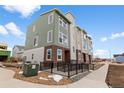 Attractive multi-story townhome featuring brick accents, muted green siding, and a black metal railing at 14283 Currant St, Broomfield, CO 80020