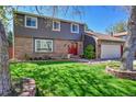 Beautifully maintained two-story house featuring a vibrant green lawn, mature tree, and inviting red front doors at 6527 S Yarrow Way, Littleton, CO 80123