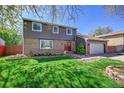 Beautifully maintained two-story house featuring a vibrant green lawn, mature tree, and inviting red front doors at 6527 S Yarrow Way, Littleton, CO 80123