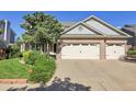 Home featuring a spacious three-car garage and beautifully landscaped front yard with mature trees at 2742 S Braun Way, Lakewood, CO 80228