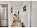 Long hallway view with stainless steel refrigerator, wood floors, and a glimpse of the living room beyond at 266 S Nome St, Aurora, CO 80012