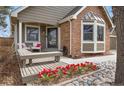 Charming covered front porch with decorative brick, bench seating, and red tulips at 16750 E Prentice Ave, Centennial, CO 80015