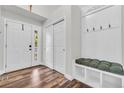 Inviting entryway with wood floors, white bench and storage, and bright lighting at 154 Falcon Cir, Mead, CO 80542