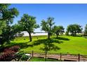 Expansive green backyard with mature trees offering shade and a view of the serene lake beyond at 4814 S Upham Ct, Littleton, CO 80123