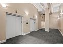 Hallway with two elevator doors, neutral paint, carpeted floors, and modern lighting fixtures at 1555 California St # 419, Denver, CO 80202